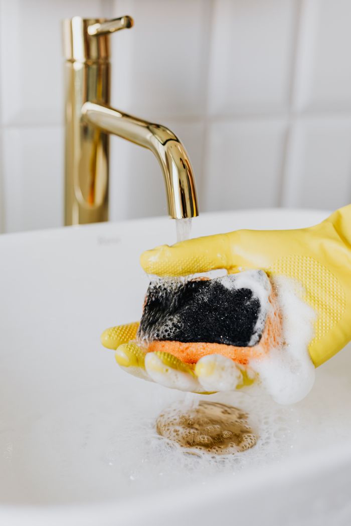 The Art of Drawing Readers In: Your attractive post title goes here Crop unrecognizable person in yellow latex protective glove rinsing sponge with detergent under stream of water in bathroom sink